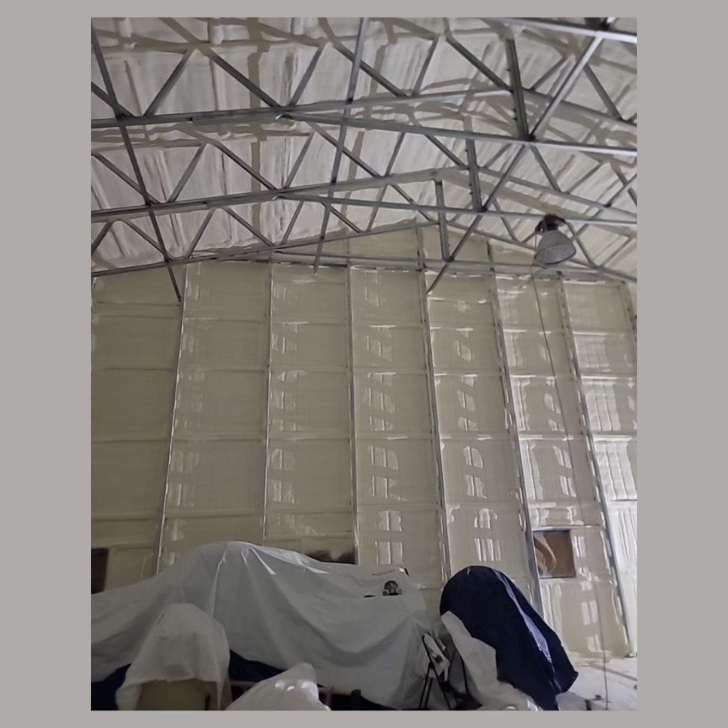 An image of a newly spray foamed metal barn. The image shows the wall from floor to ceiling.