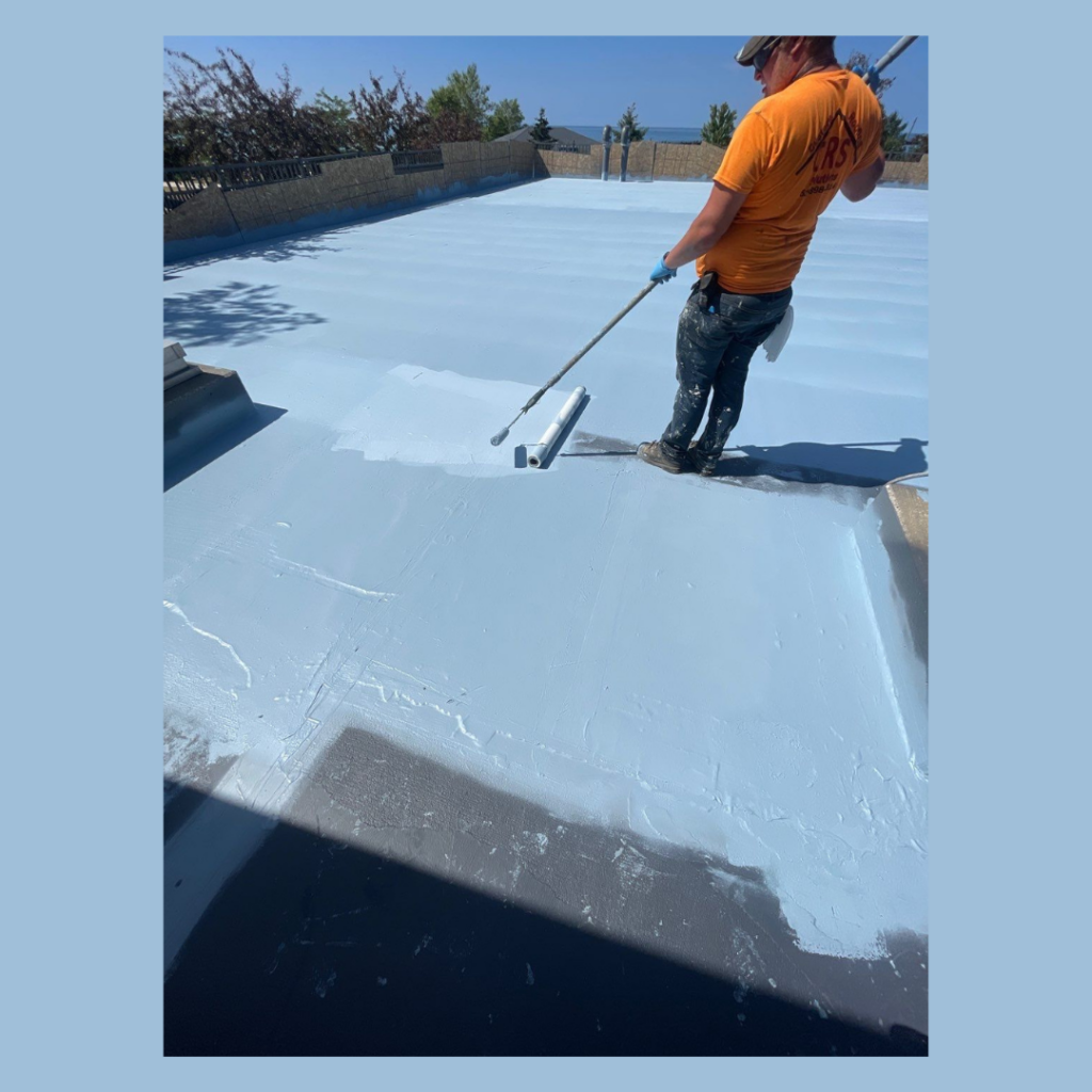 Commercial Roofing contractor applying roof coatings to a commercial roof with a roller.